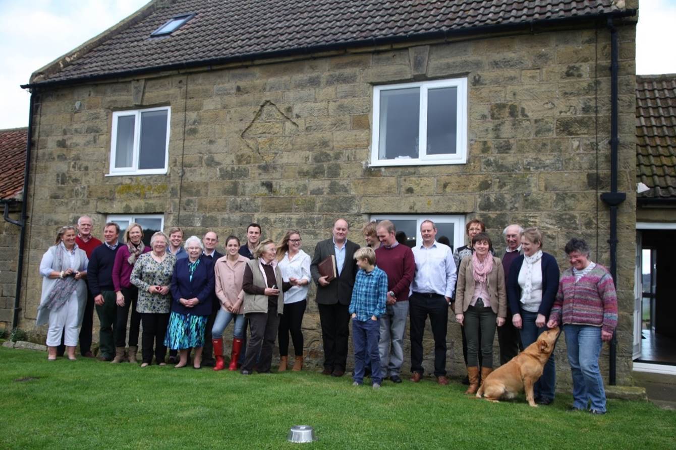 A group of people standing in front of a house
Description automatically generated